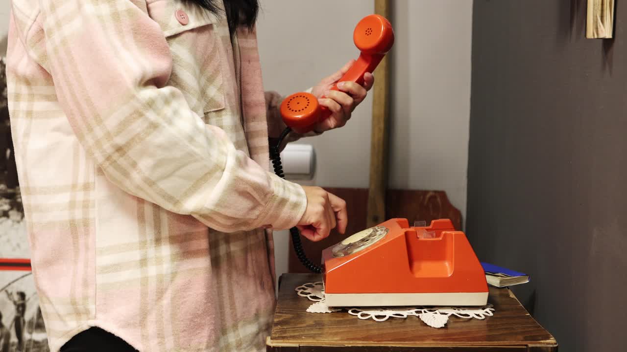 오래 된 빨간 전화에 전화를 거는 여자의 자른된 측면 초상화