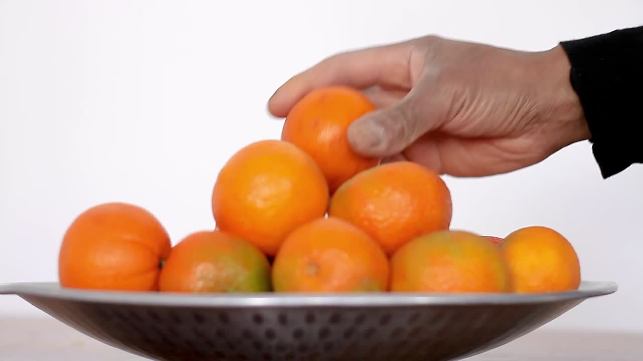 건강한 식습관을 홍보하는 오렌지와 감귤 한 그릇에서 오렌지 과일을 선택하려는 남자 스톡 비디오 스톡 푸티지