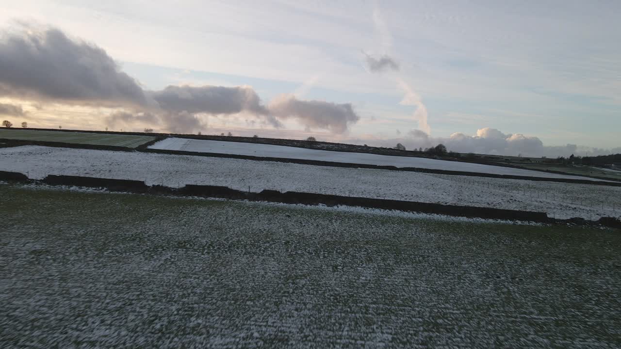 A panning drone shot flying over frozen fields at sunset.