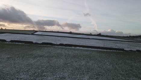 a panning drone shot flying over frozen fields at sunset.