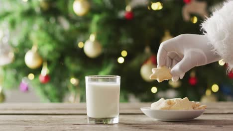 santa claus sumerge la galleta en leche sobre el árbol de navidad y las luces