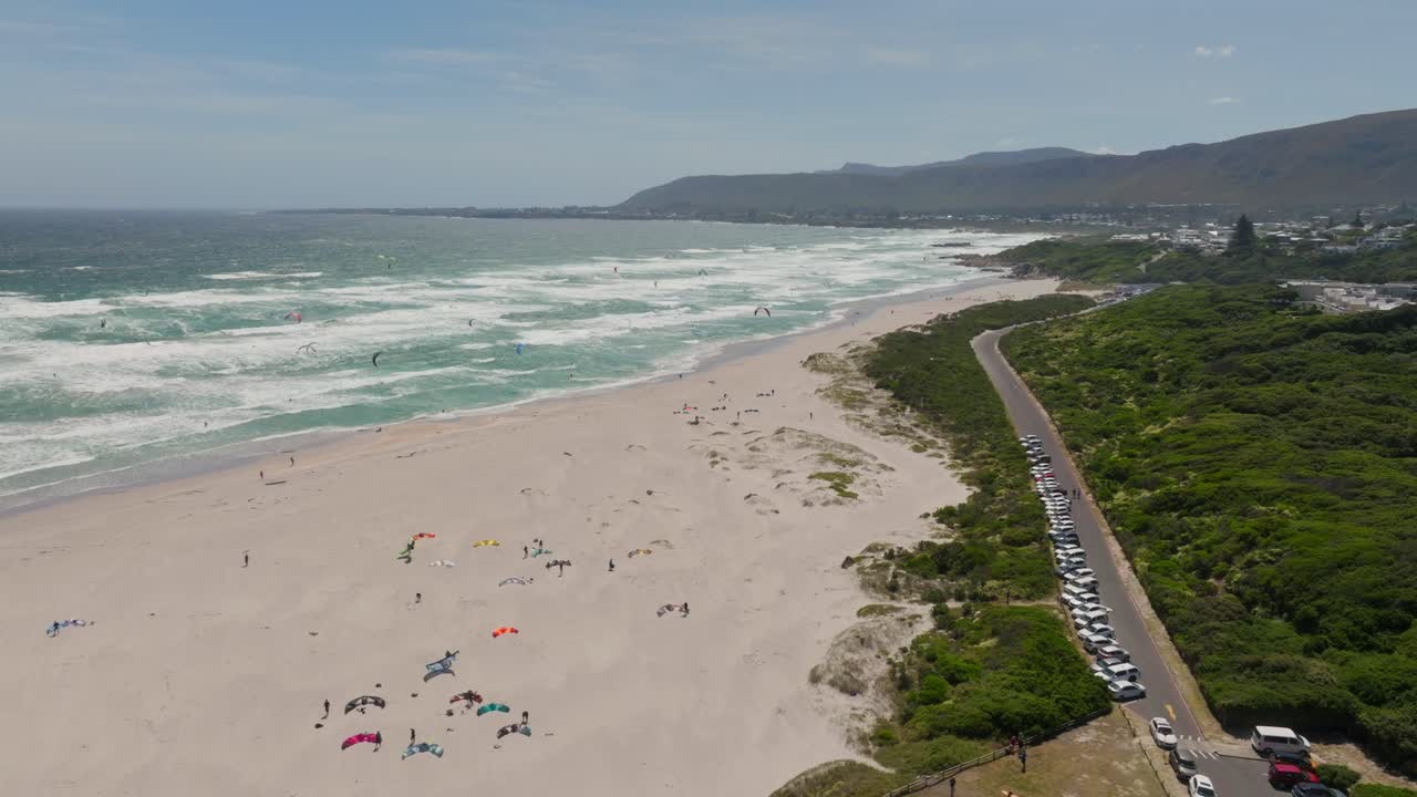 Aerial view of Hermanus beach with ocean waves, road, and lush greenery