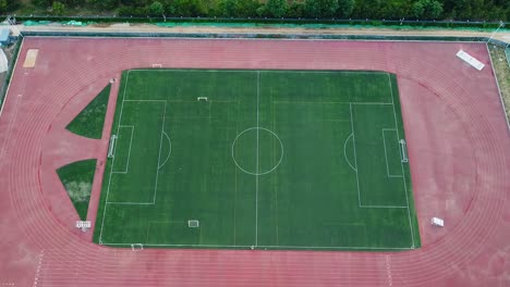 Exercising-at-soccer-football-field---cinematic-aerial-drone-shot-view