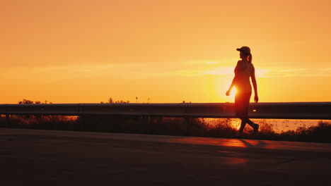 walking to promote health in a beautiful place silhouette of a woman walking along the road against