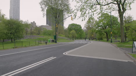 camera tilt down from bike approaching to road surface — painted pedestrian symbols with surgical mask and hand sanitizer, central park, new york city