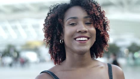 Front-view-of-smiling-curly-lady-standing-on-street