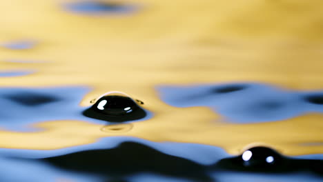 close up real of water drop falls into water and diverging circles of water with smoot color background in studio with copy space for place a text for advertisement