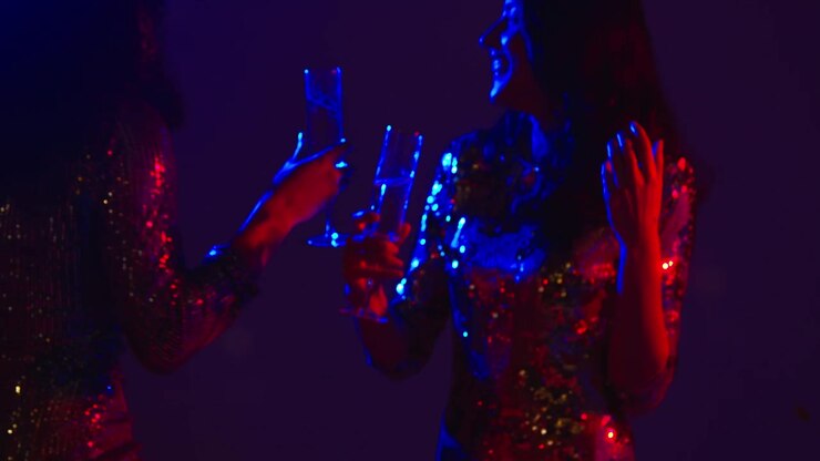 Primo piano di due donne in un nightclub, bar o discoteca che ballano e bevono alcolici con coriandoli di carta 1