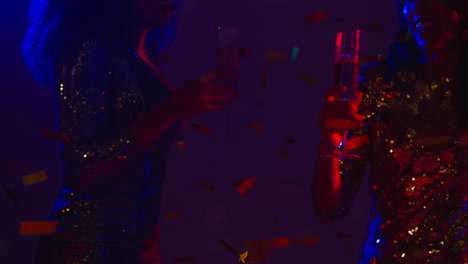 cerca de dos mujeres en un bar de club nocturno o discoteca bailando y bebiendo alcohol con confeti de papel 1