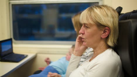 Mujer-En-El-Tren-Hablando-Por-Teléfono,-Madre-E-Hijo-Viendo-Un-Vídeo.