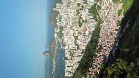 vertical drone shot over favela slum and cityscape of rio de janeiro during sunny day in brazil