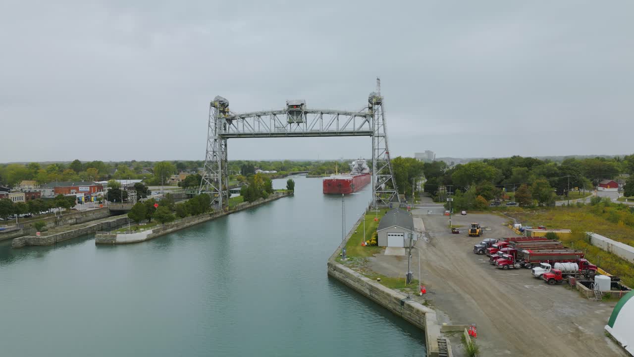 The Port Colborne vertical-lift bridge is raised, while a red laker boat comes down the canal