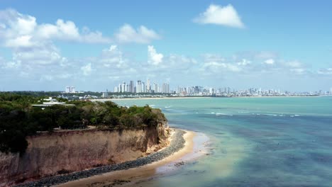 trucking right aerial drone shot of the tropical beach capital city of joao pessoa, paraiba, brazil from the touristy cabo branco cliffs with stunning clear turquoise ocean water on a summer day