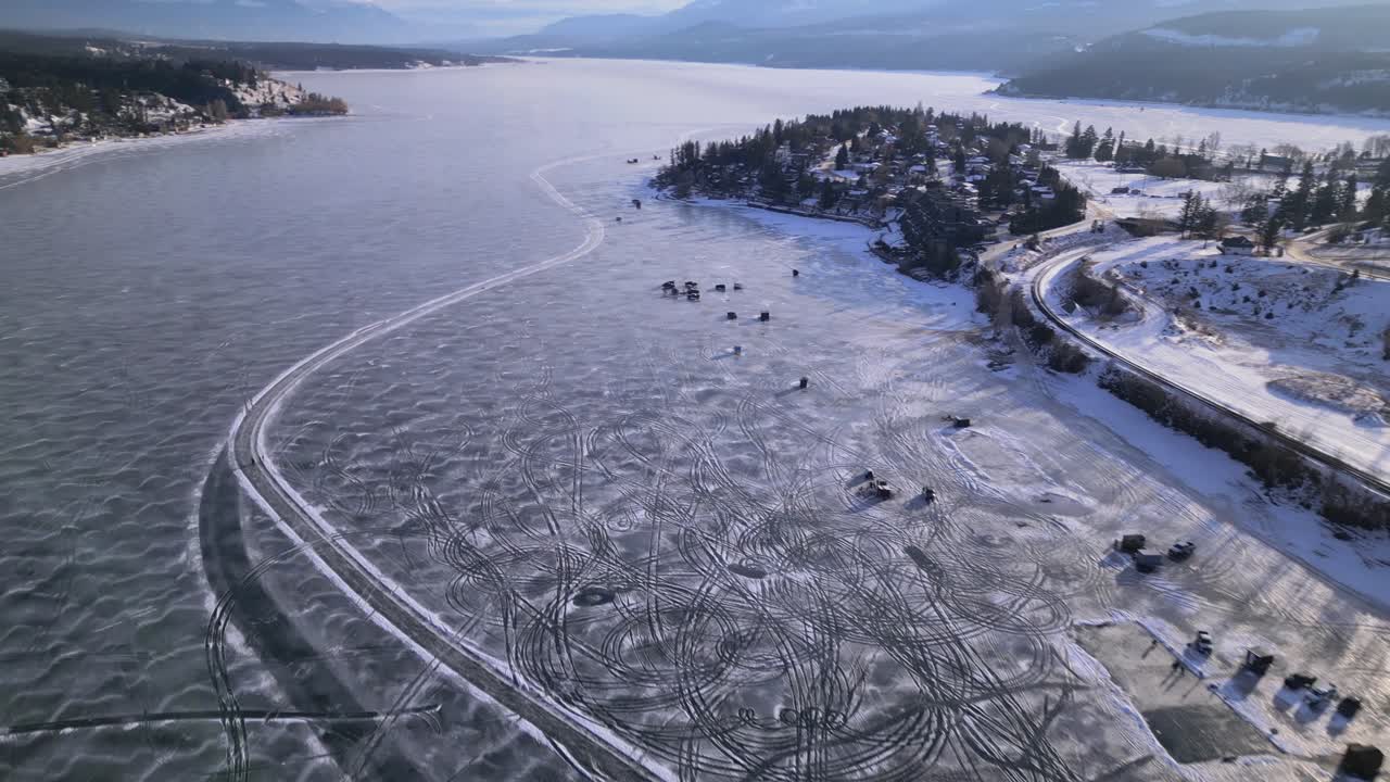 vista aérea de drones del lago windermere congelado sobre el paso por encima de la ciudad de windermere con pesca en hielo y pistas artificiales hechas en el hielo debajo