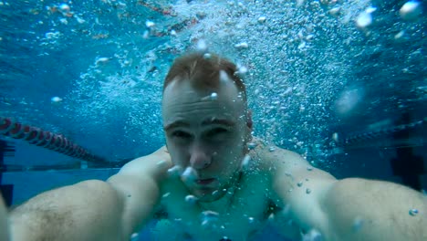 man looking straight into the camera and holding it before diving headlong into the water