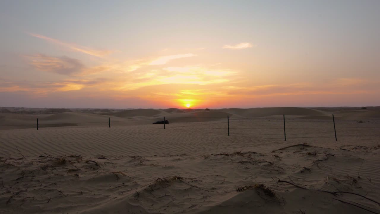 ascendiendo sobre la duna de arena del desierto de abu dhabi para revelar una maravillosa puesta de sol naranja y rosa sobre el horizonte