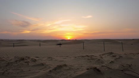 ascending over abu dhabi desert sand dune to reveal marvelous orange and pink sun setting over horizon