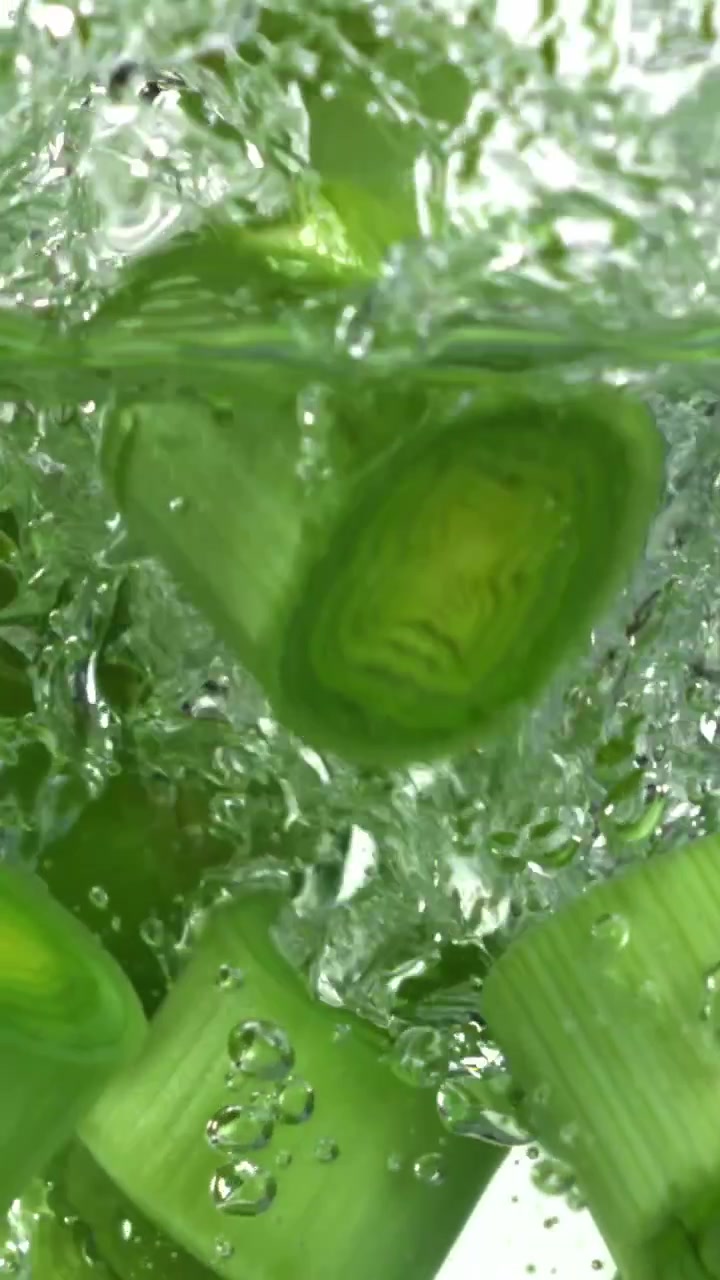 Verdure verdi affettate che schizzano in acqua limpida