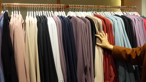 a woman browsing through a rack of clothing in a boutique