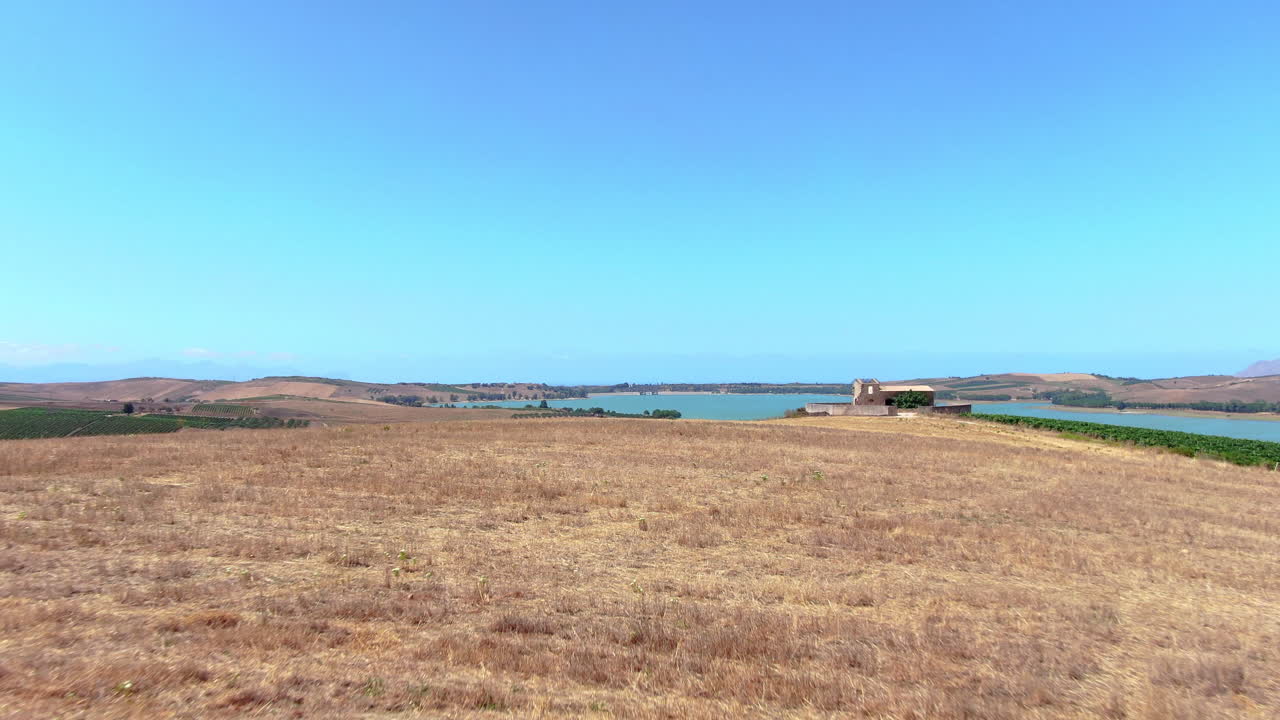 vista aérea de ángulo bajo de cultivos secos con vista al lago poma, sicilia