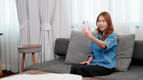 portrait of asian young woman video call with smartphone at home