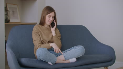 Happy-young-lady-student-is-talking-on-mobile-phone-holding-smartphone-in-apartment.-Modern-communication-cheerful-millennials-and-leisure-time-concept.