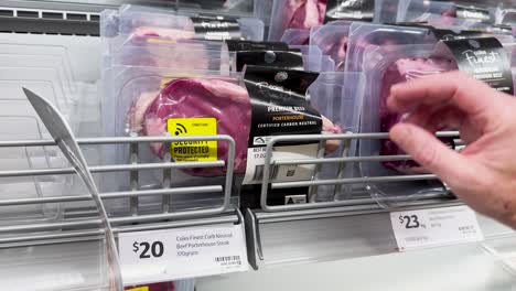 persona que elige carne envasada en una tienda