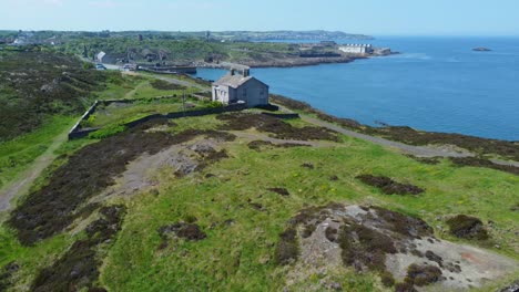 abandoned amlwch coastal countryside mountain house aerial view overlooking anglesey harbour pull back