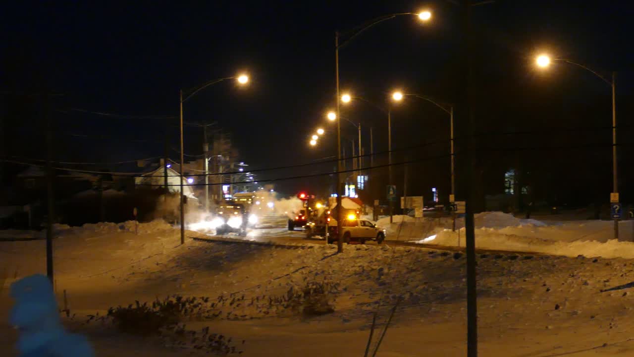 sartén de izquierda a derecha, trabajadores de la ciudad limpiando la carretera de la nieve por la noche en invierno, limpiando la carretera de la tormenta de nieve