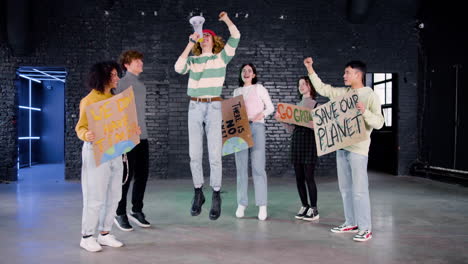 happy young environmental activists with placards and megaphone jumping and protesting against climate change inaction