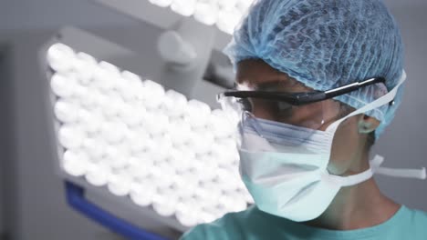 African-american-female-doctor-wearing-face-mask-in-hospital-operating-room,-slow-motion