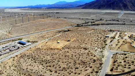 Fly-in-across-barren-desert-part-3,-Interstate-10-freeway,-windmills,-wind-turbines-energy,-green,-renewable,-huge-power-generating-farm,-Palm-Springs,-Coachella-Valley,-aerial-4k-drone,-Cabazon,-CA