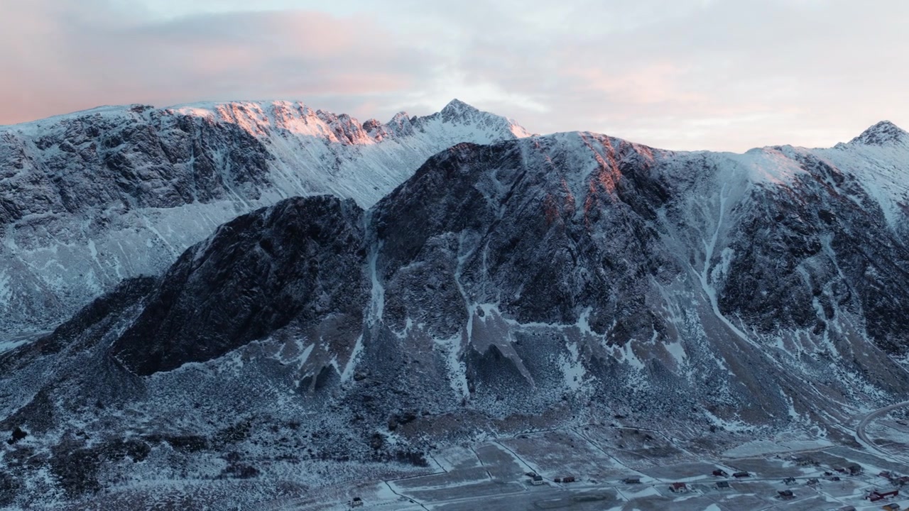 Cordilheira ártica acidentada coberta de neve sob um horizonte de inverno nublado, drone estabelecendo o fundo.