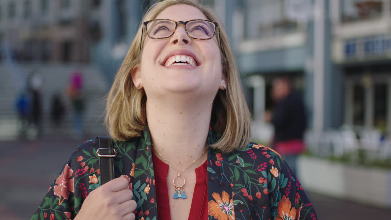 retrato de una mujer de negocios rubia de moda riendo feliz con gafas camisa floral disfrutando de los viajes urbanos