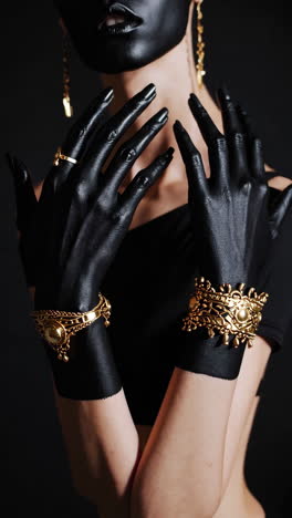 mysterious figure with black painted hands and gold ornate jewelry