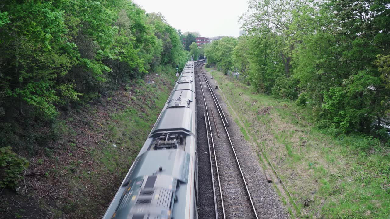 High angle view of a train going forward to the station between the green trees and beautiful forest nature during daytime