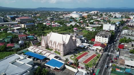 Orbiting-aerial-shot-of-idyllic-Iglesia-ni-Cristo-church-in-the-middle-of-busy,-provincial-town-of-Legazpi,-Albay