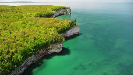 aerial pan up coast of sandstone rock cliffs with sea arch, pictured rocks national lakeshore, munising, michigan