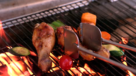 chicken drumsticks being cooked on flaming barbecue