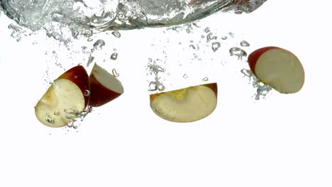 Apple-segments-plunging-into-water-on-white-background