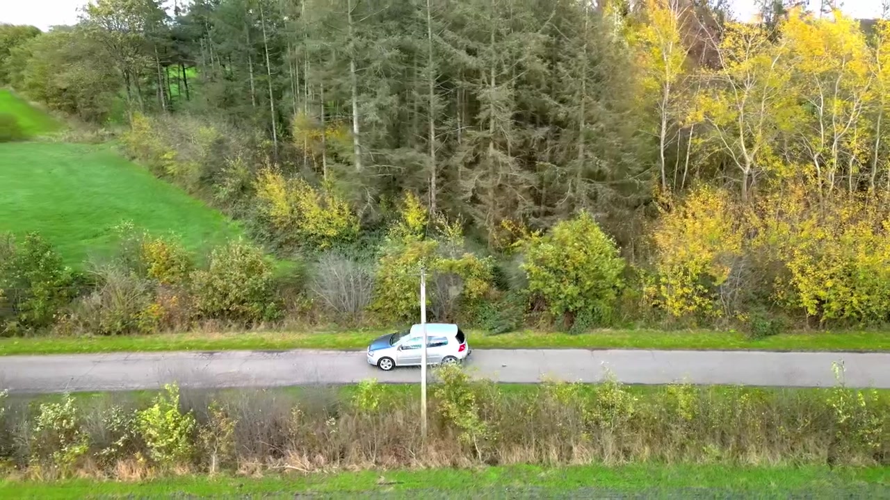 Zijaanzicht van een gevolgde auto op een kleine verharde weg.