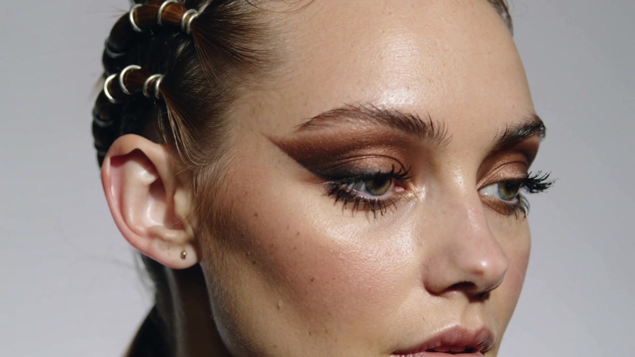 Turning model responding to director cue, moving gaze on set, showing bronze shadow and metal rings