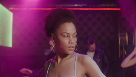 portrait of beautiful girl looking confident at camera at disco while her friends dancing behind her 1