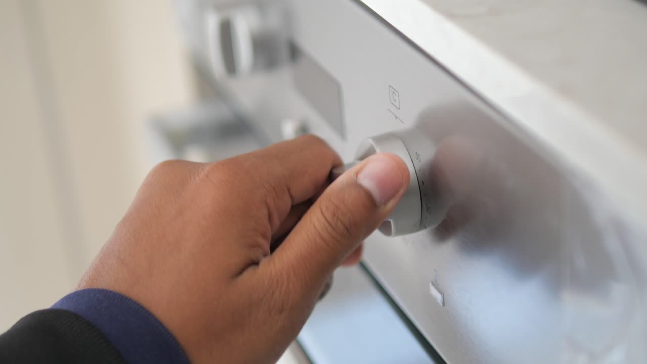 오븐 의 손잡이 를 돌리는 손 의 클로즈업