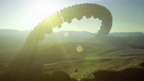 unidentified alien ship hovers over mountainous terrain during bright sunset