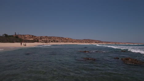 drone de bajo vuelo sobre las aguas del océano en la playa rocosa en cabo san lucas, méxico