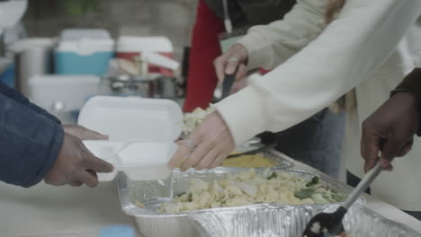 people serving food at an outdoor community event