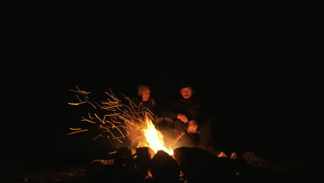 una pareja junto a una fogata por la noche