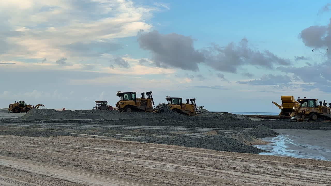 Wide view, beach sand replenishment, construction equipment moving
