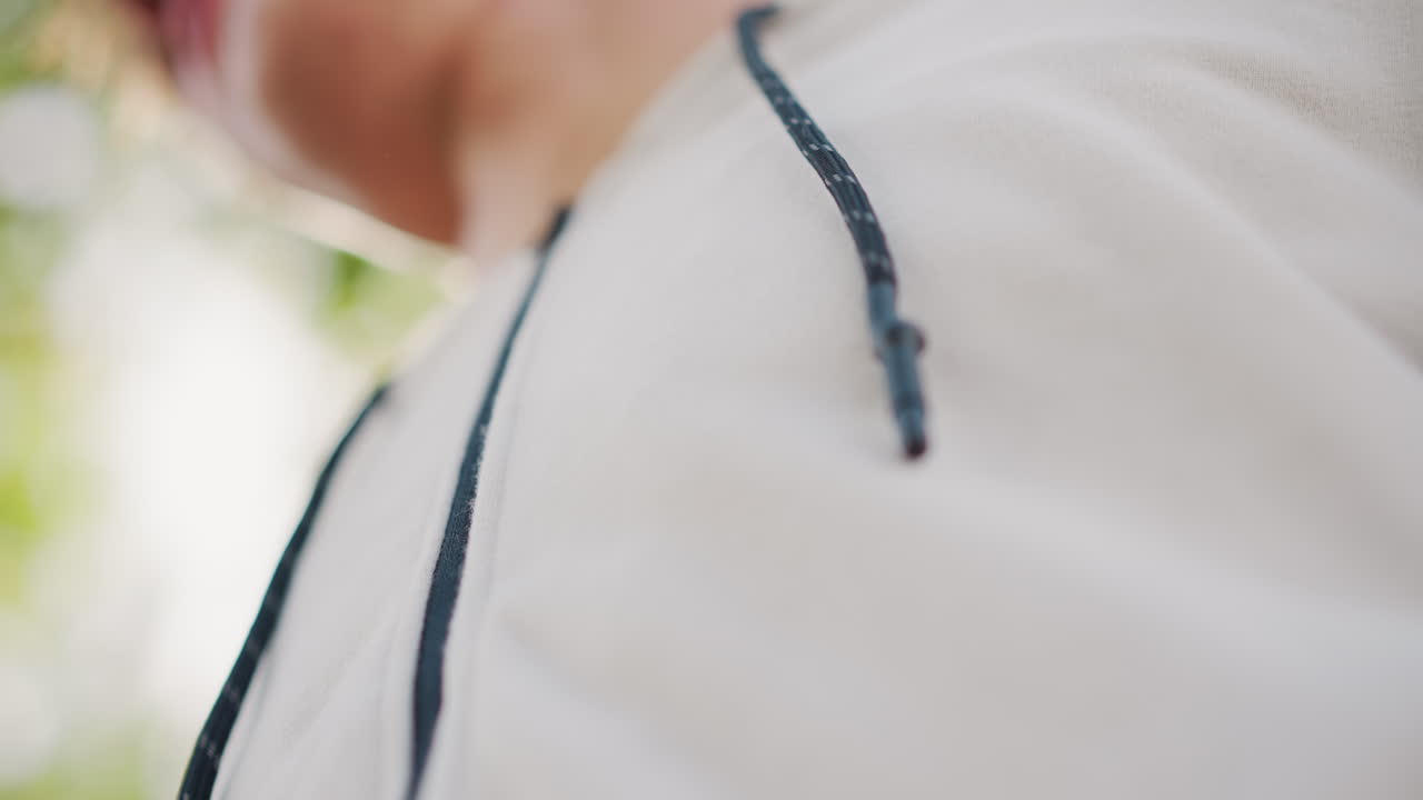 달리기 전에 후드티 지퍼를 올리는 손, 녹색 보케와 흐린 하늘 아래 흰색 후드티의 지퍼를 채우는 손 클로즈업, 질감 있는 원단, 상쾌한 아침의 활기, 조깅을 준비하는 러너